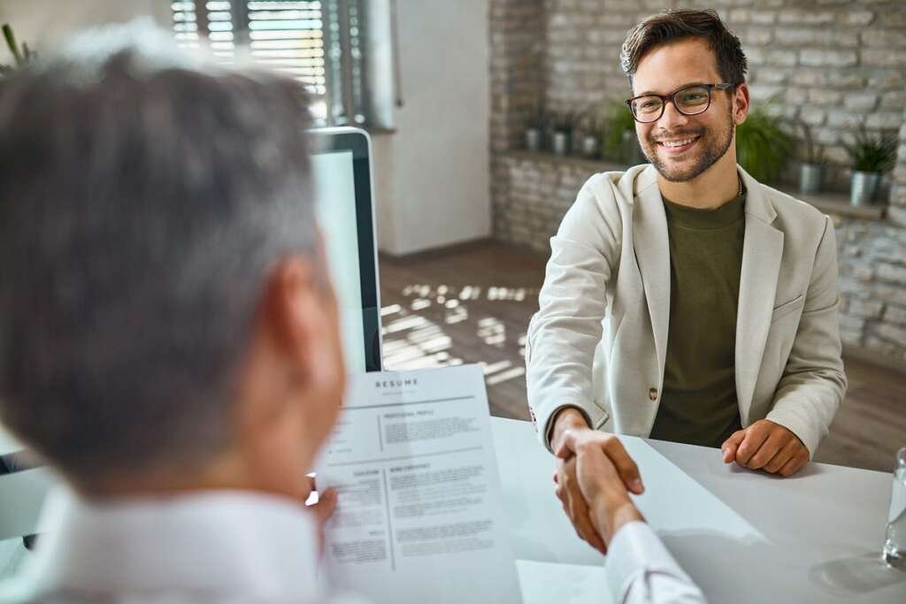 panel interview setup at an architecture firm, with candidates seated across a table from senior architects reviewing portfolios and asking questions—depicting a real-world junior architect interview scenario.