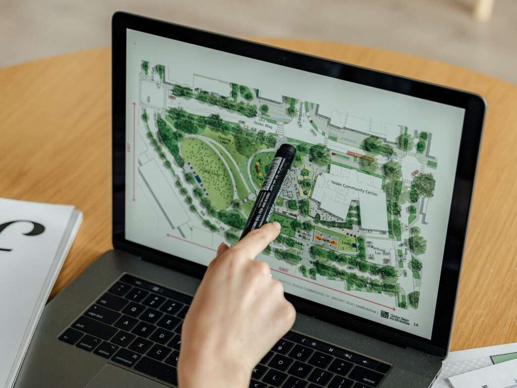 a sustainability specialist architect pointing to a design plan on the laptop screen