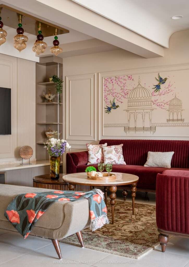 indian living room with heritage art on wall & maroon luxury sofa with wooden tables